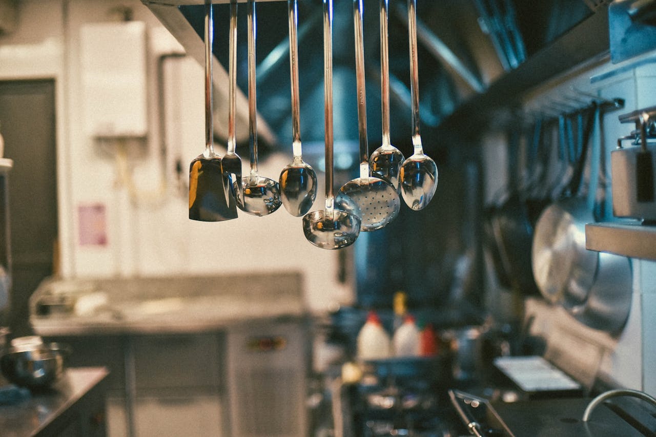 The Art of Drawing Readers In: Your attractive post title goes here Stainless steel kitchen utensils hanging in a modern kitchen setting with blurred background.