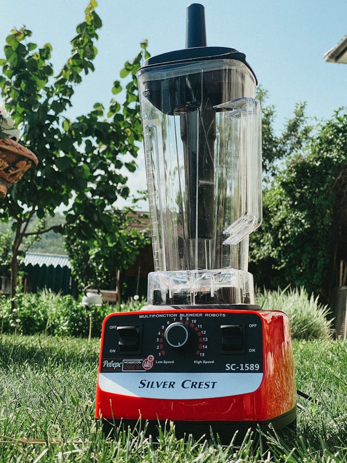 gallery-5 Red Silver Crest blender placed in a sunny outdoor garden setting.