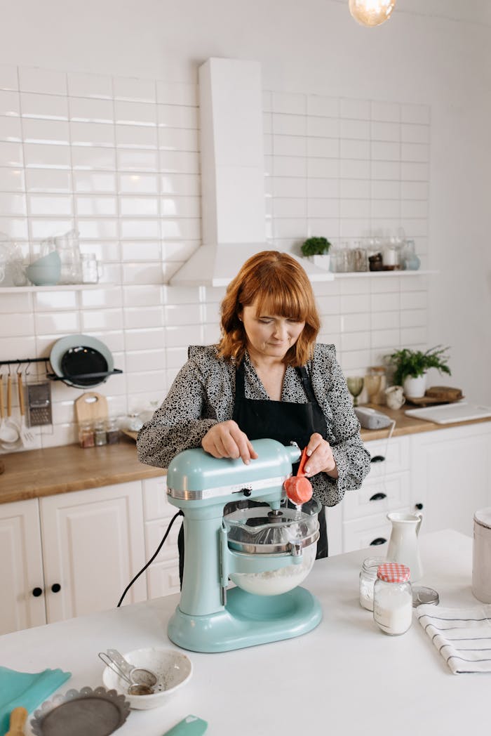 gallery-6 A woman pours ingredients into a mixer while baking in a stylish modern kitchen.
